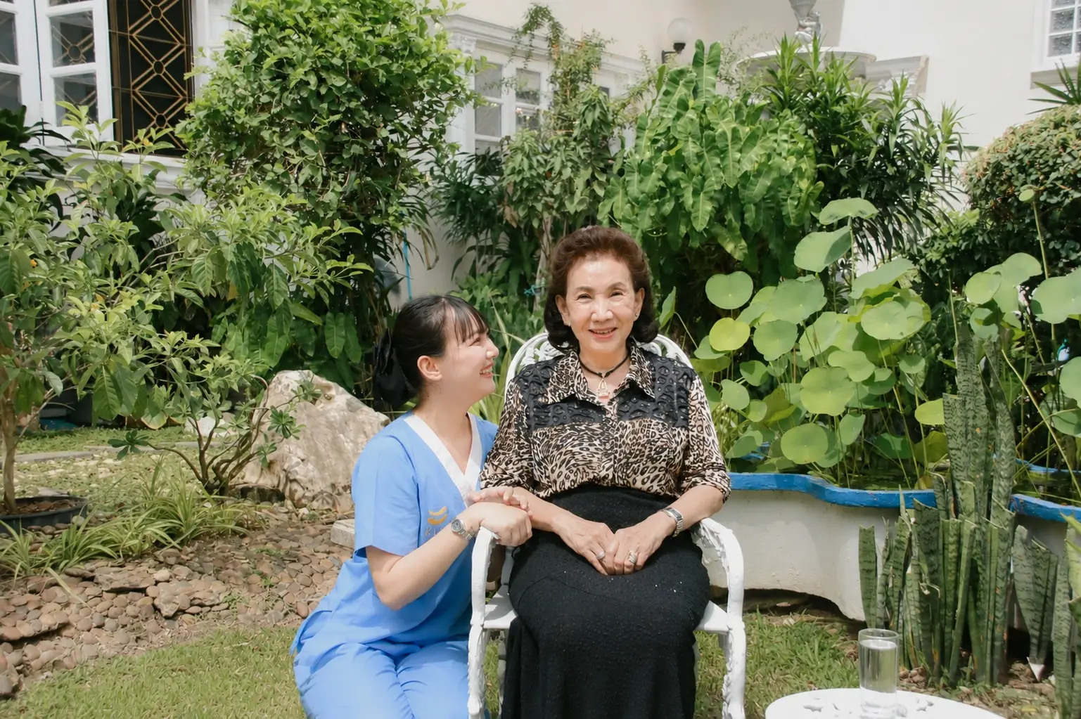 ผู้ดูแล KIN นั่งพูดคุยอบอุ่นกับผู้สูงอายุในสวนบ้าน จัดหาผู้ดูแล KIN HomeCare